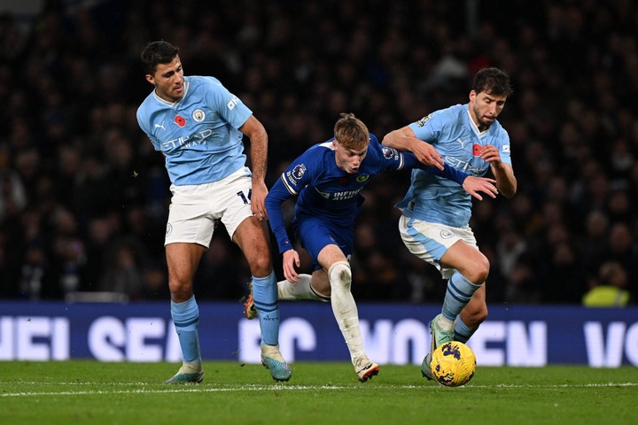 Cole Palmer of Chelsea is challenged by Rodri and Ruben Dias of Manchester City during the Premier League match between Chelsea FC and Manchester C...