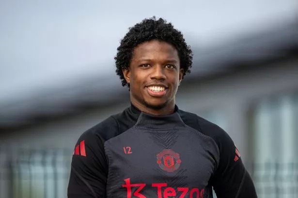 Tyrell Malacia smiles as he walks out onto one of the Carrington training pitches.