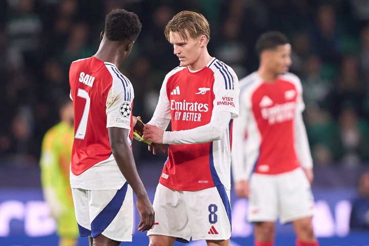 Martin Odegaard of Arsenal FC gives the captain's armband to Buyako Saka of Arsenal FC during the UEFA Champions League match between Sporting CP a...