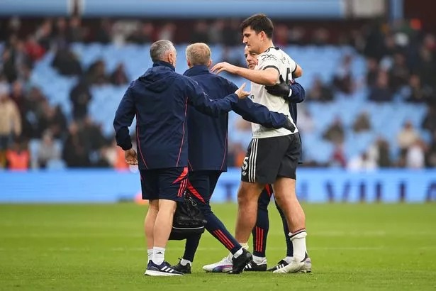 Harry Maguire is assisted off the pitch at Villa Park by Manchester United's medical staff.