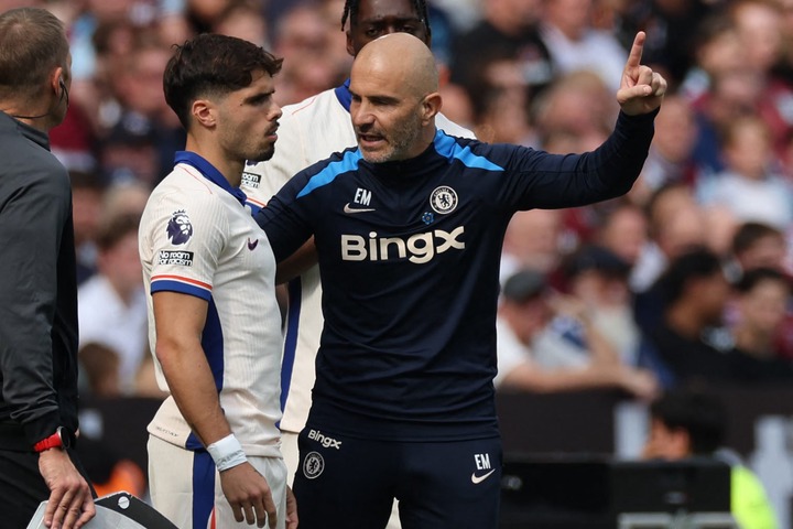 Chelsea's Italian head coach Enzo Maresca (R) speaks with Chelsea's Portuguese midfielder #07 Pedro Neto (L) as he prepares to come on as a substit...