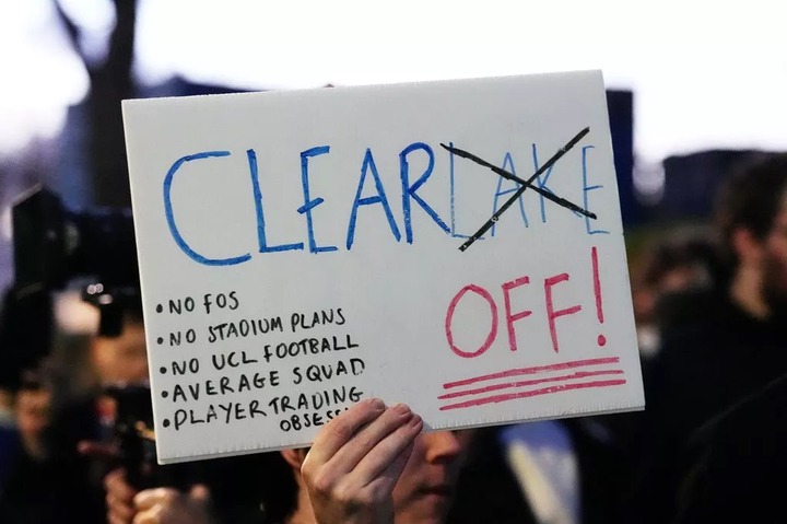 A Chelsea fan holding a sign during a fan organized protest against the clubs ownership outside Stamford Bridge